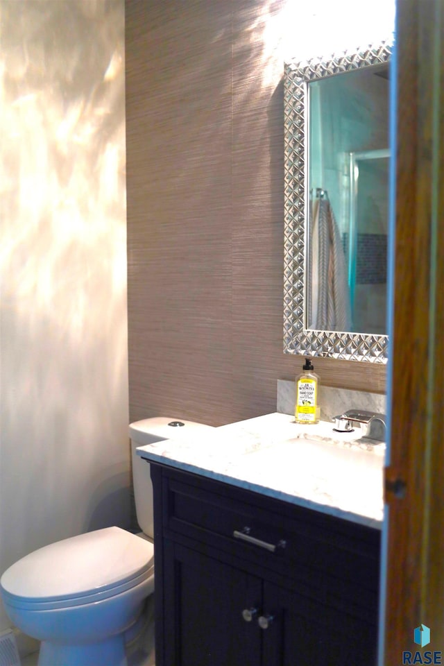 bathroom featuring toilet, vanity, a shower with door, and tile walls