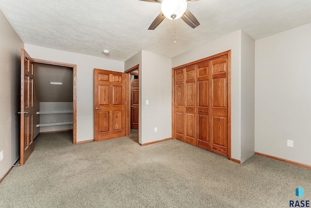 unfurnished bedroom featuring a textured ceiling, baseboards, a closet, and carpet flooring