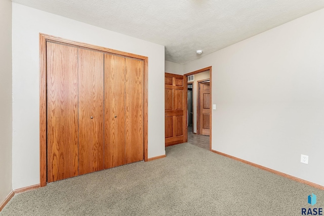 unfurnished bedroom featuring light carpet, visible vents, baseboards, a textured ceiling, and a closet