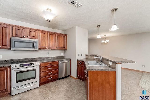 kitchen featuring a peninsula, a sink, visible vents, appliances with stainless steel finishes, and decorative light fixtures