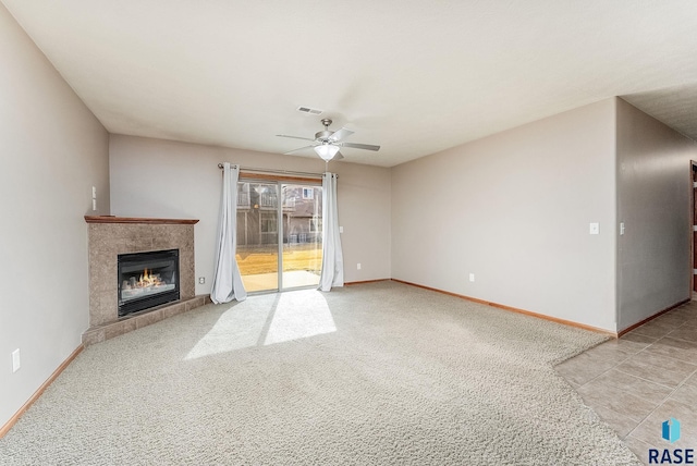 unfurnished living room with visible vents, a tiled fireplace, a ceiling fan, light carpet, and baseboards