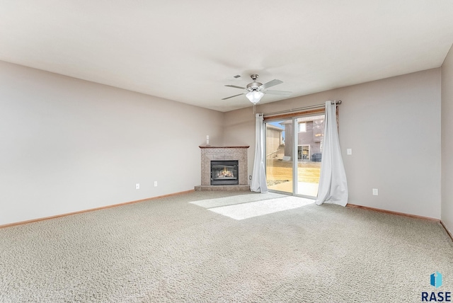 unfurnished living room featuring carpet, baseboards, ceiling fan, and a tiled fireplace