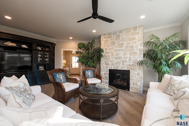 living room featuring recessed lighting, a fireplace, crown molding, and wood finished floors