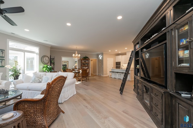 living room with light wood finished floors, ceiling fan with notable chandelier, ornamental molding, and recessed lighting