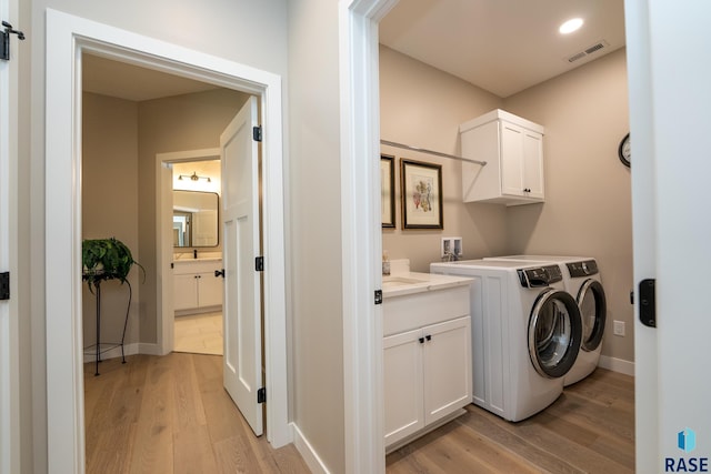 clothes washing area with washing machine and dryer, visible vents, baseboards, light wood-type flooring, and cabinet space