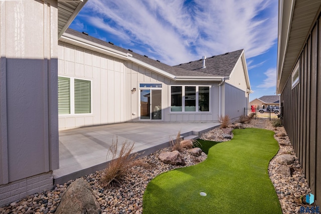 back of house featuring board and batten siding, a patio area, fence, and a shingled roof