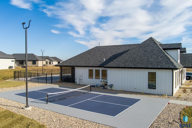 exterior space with a tennis court and fence