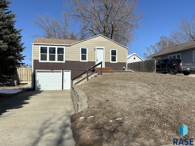 view of front of property with driveway, an attached garage, and fence