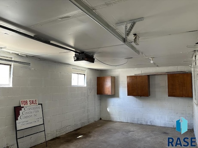 garage with a garage door opener and concrete block wall