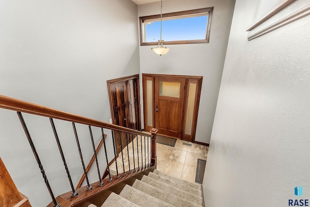 foyer entrance featuring baseboards, visible vents, a high ceiling, and stairs