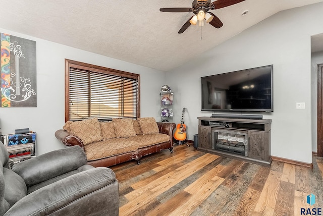 living room with baseboards, a ceiling fan, lofted ceiling, wood finished floors, and a textured ceiling