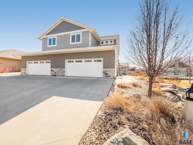 craftsman-style home with a garage, stone siding, and driveway