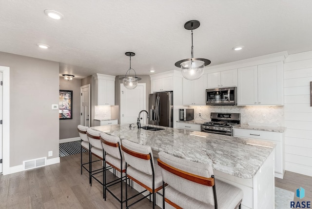 kitchen featuring light wood-style flooring, white cabinetry, visible vents, appliances with stainless steel finishes, and decorative backsplash