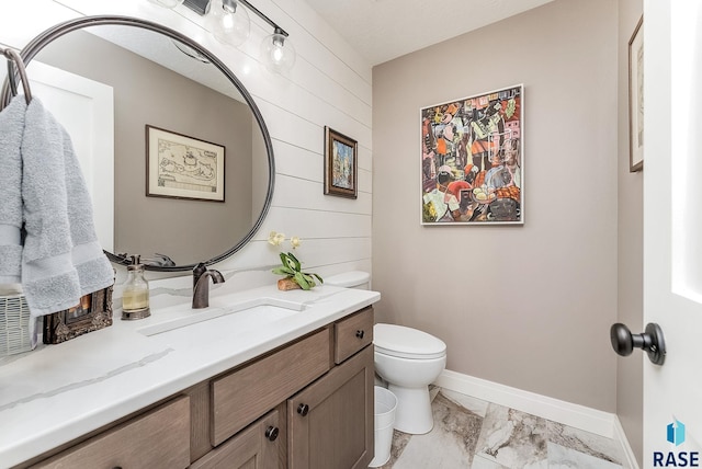 bathroom featuring marble finish floor, baseboards, vanity, and toilet