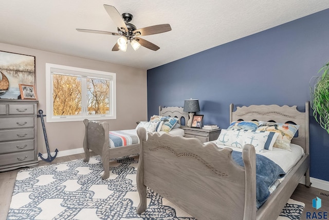 bedroom with ceiling fan, wood finished floors, and baseboards