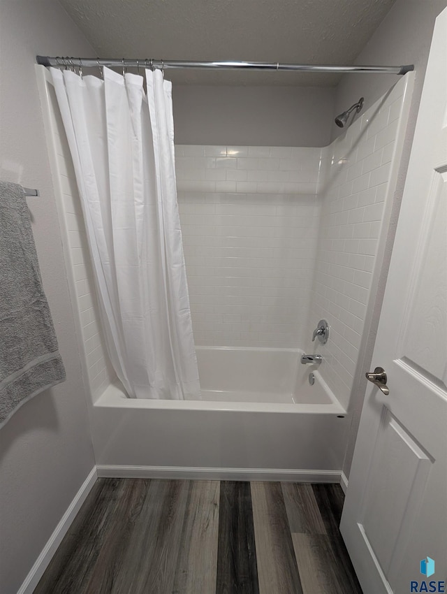 bathroom featuring shower / tub combo, wood finished floors, and baseboards