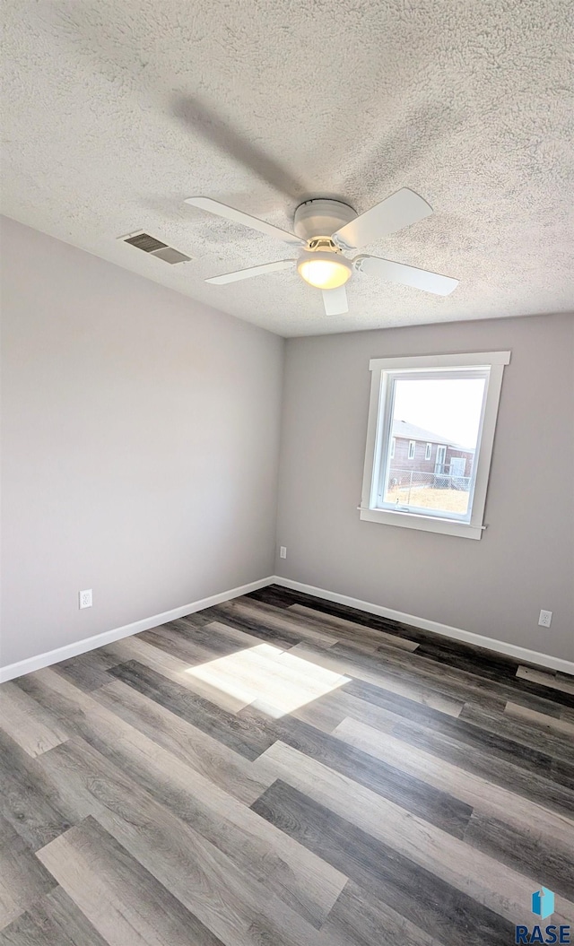 empty room with visible vents, baseboards, ceiling fan, and wood finished floors