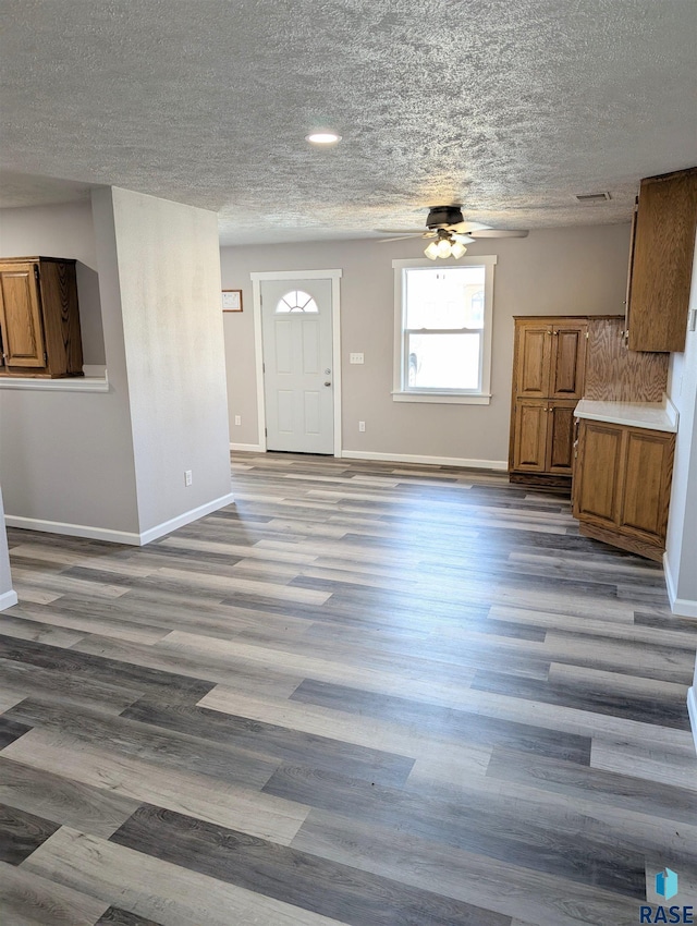 interior space with a textured ceiling, baseboards, and wood finished floors