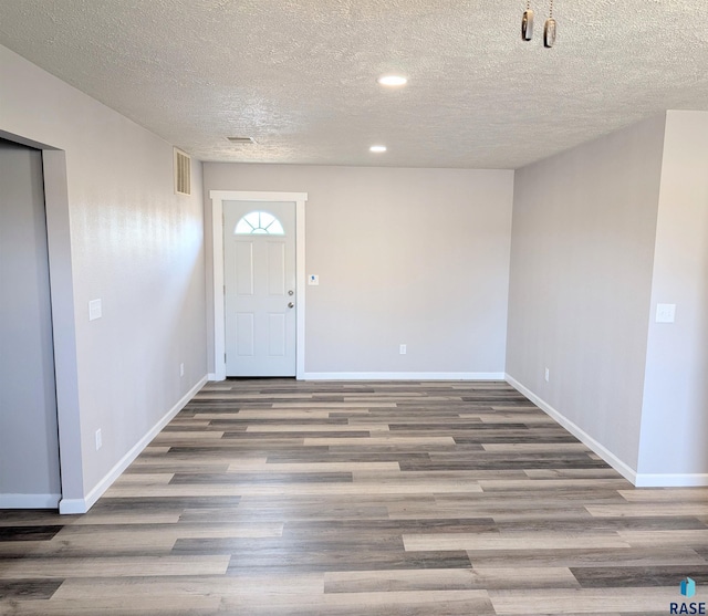 entrance foyer featuring visible vents, baseboards, wood finished floors, a textured ceiling, and recessed lighting