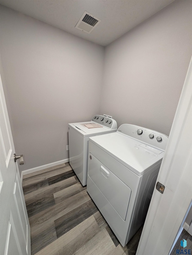 washroom with visible vents, washing machine and dryer, light wood-type flooring, laundry area, and baseboards