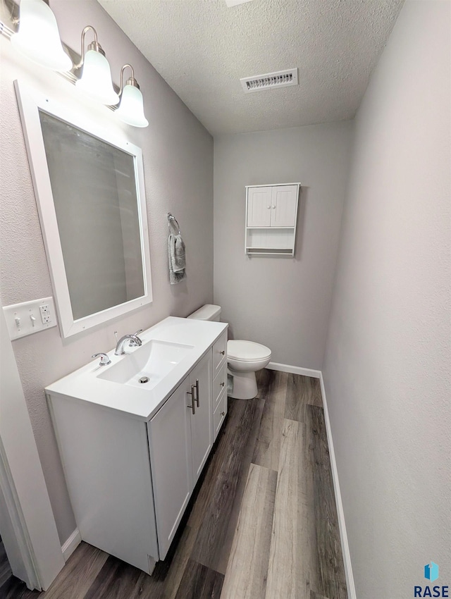 bathroom with visible vents, vanity, wood finished floors, and toilet