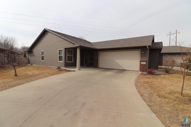 single story home featuring a shingled roof, brick siding, driveway, and an attached garage