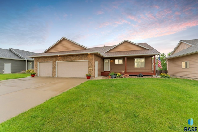 ranch-style home featuring driveway, a yard, an attached garage, a shingled roof, and brick siding