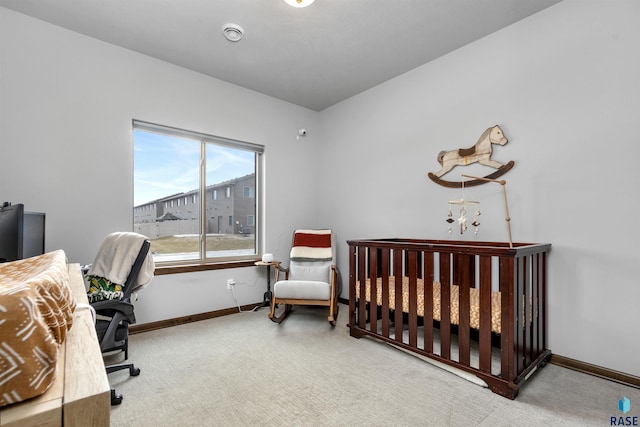 carpeted bedroom with a crib and baseboards