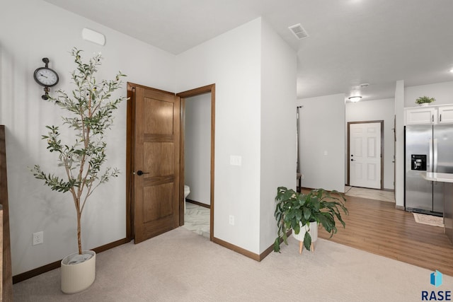 interior space featuring visible vents, light colored carpet, and baseboards