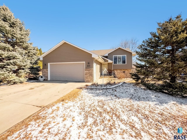 tri-level home with concrete driveway, brick siding, and a garage