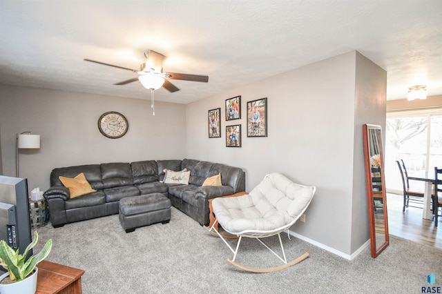 carpeted living area with baseboards and a ceiling fan