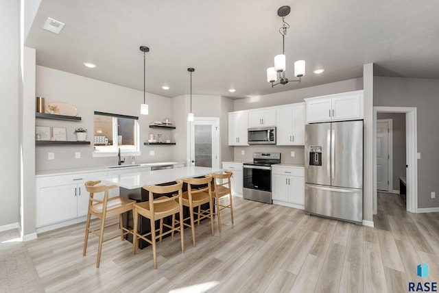 kitchen with open shelves, a sink, a center island, stainless steel appliances, and light countertops