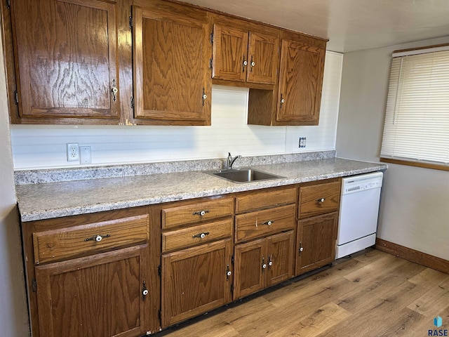 kitchen with a sink, light wood-type flooring, dishwasher, and brown cabinetry