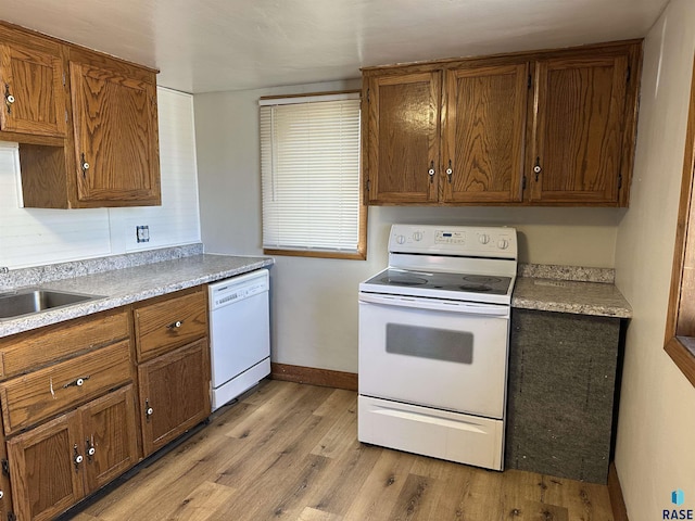 kitchen with light wood-type flooring, a sink, white appliances, light countertops, and baseboards