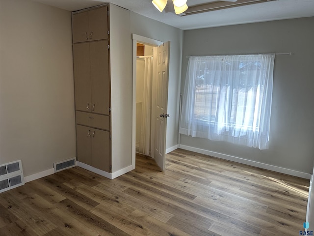 unfurnished bedroom featuring light wood finished floors, visible vents, and baseboards