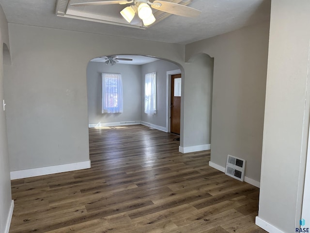 unfurnished room featuring visible vents, baseboards, wood finished floors, arched walkways, and a ceiling fan