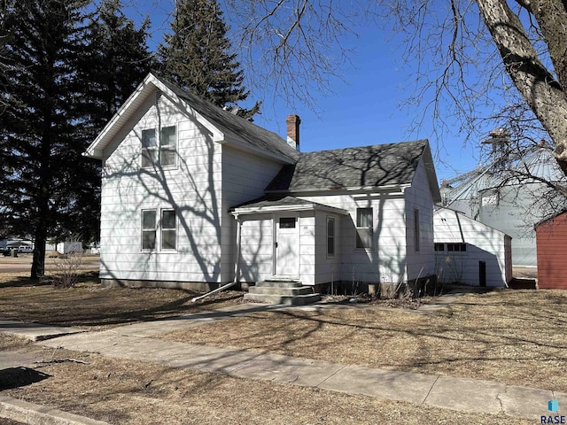 view of front of property featuring a chimney and a shingled roof