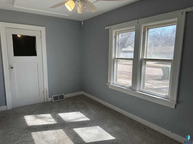 carpeted empty room featuring visible vents, baseboards, and ceiling fan