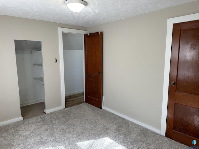 unfurnished bedroom with a closet, carpet flooring, a textured ceiling, and baseboards