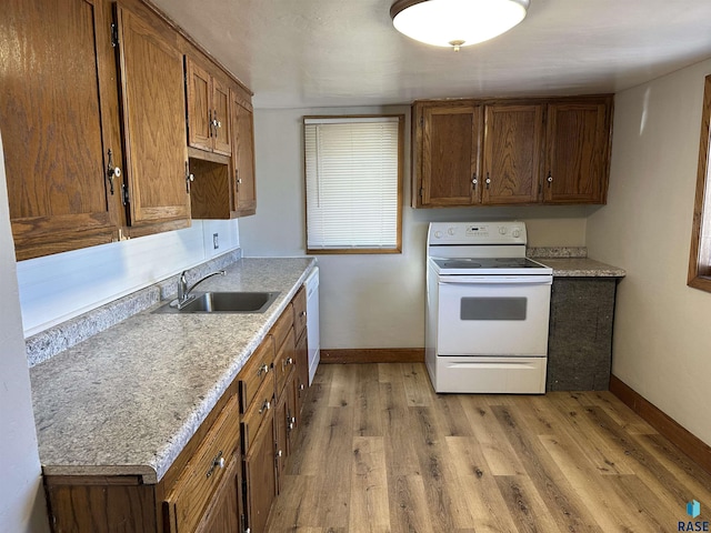 kitchen with light wood-type flooring, brown cabinets, a sink, white appliances, and baseboards