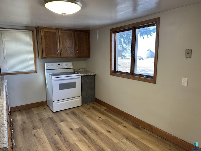 kitchen with baseboards, light wood-style flooring, light countertops, and electric stove