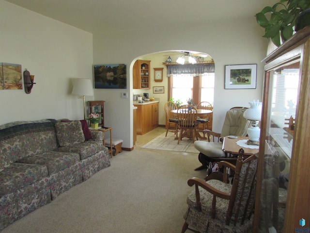 living area with arched walkways and light colored carpet