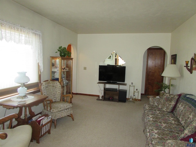 carpeted living area with arched walkways and baseboards