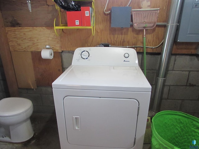 clothes washing area featuring electric panel, laundry area, washer / dryer, and concrete block wall