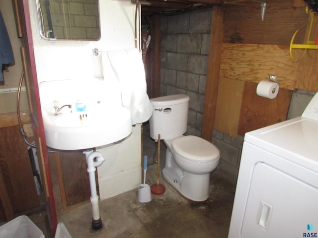 bathroom featuring washer / dryer, toilet, and concrete flooring