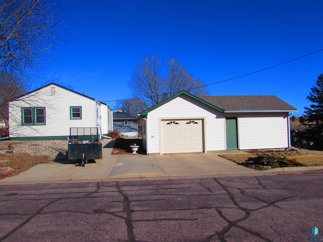 view of side of property featuring an attached garage and roof with shingles