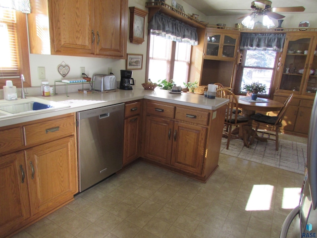 kitchen with a sink, stainless steel dishwasher, a peninsula, brown cabinetry, and light countertops