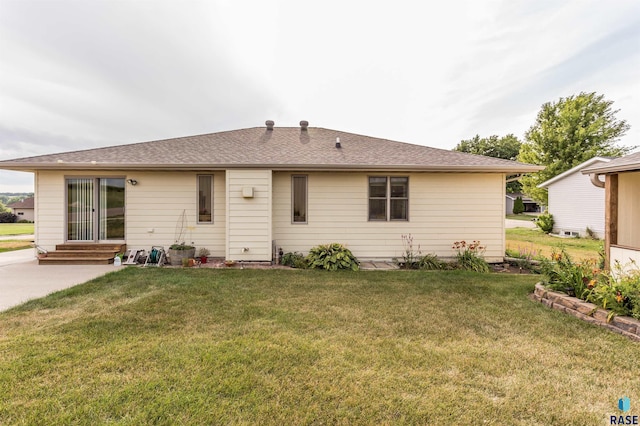 rear view of property with a yard, roof with shingles, and entry steps