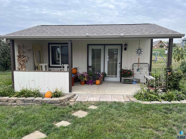 back of house with a lawn and a shingled roof