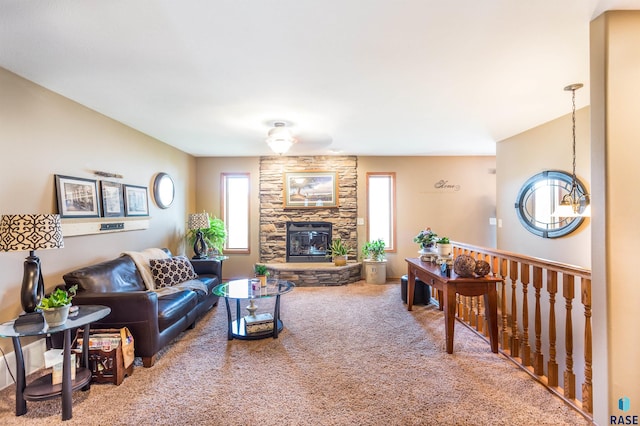 living room featuring a stone fireplace, carpet floors, and ceiling fan